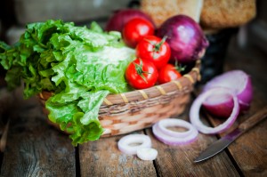 Fresh vegetables in the basket on wooden background